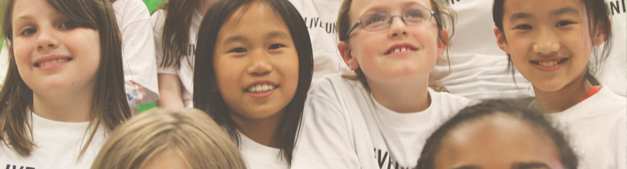 Smiling children wearing white tshirts that say LIVE UNITED