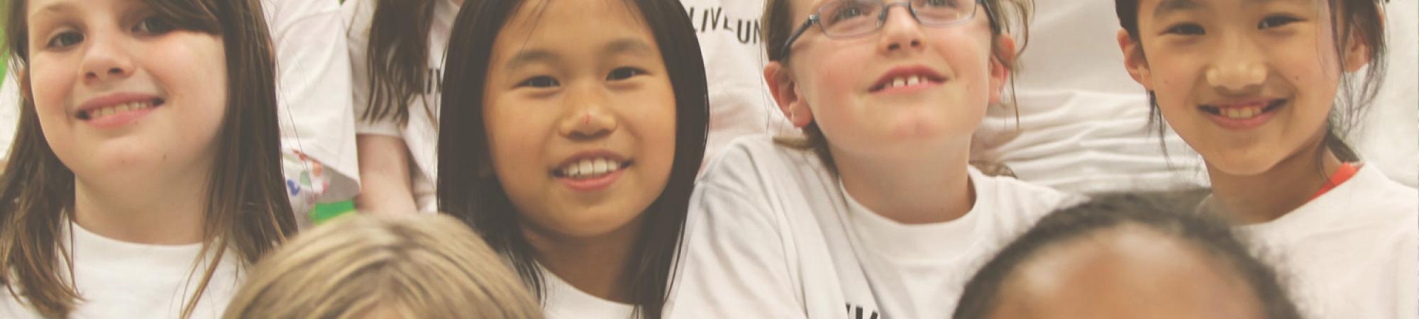 Smiling children wearing white tshirts that say LIVE UNITED